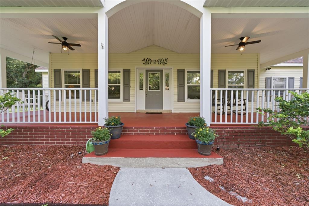 A covered front porch with white railings, a red brick base, and a central entryway — 3407 FLAGSTAFF CIRCLE, WIMAUMA, FL
