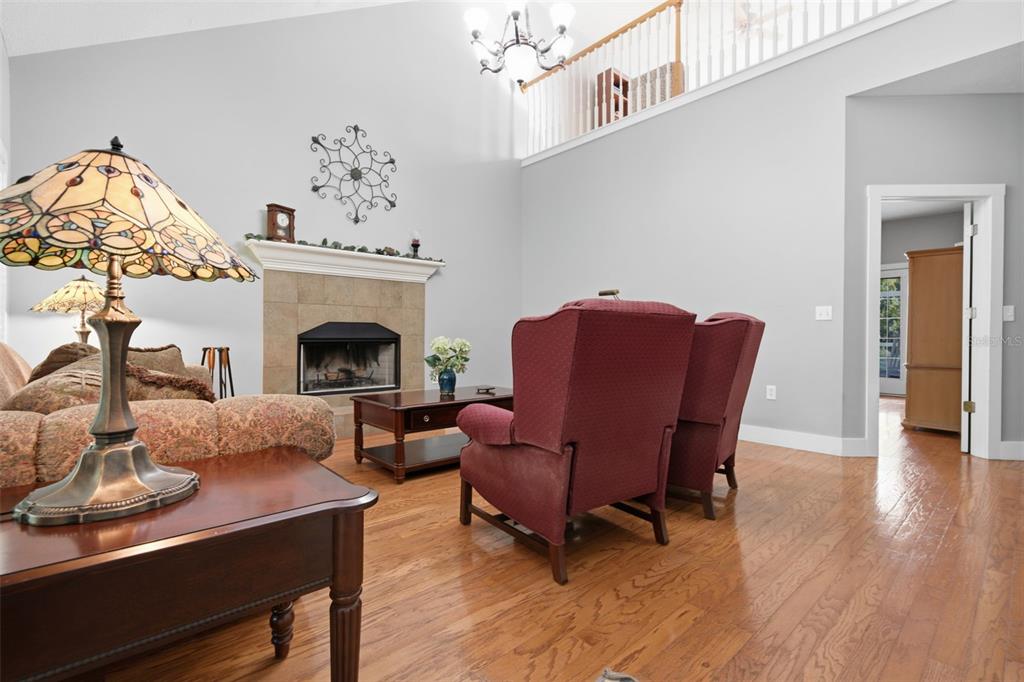 A living room features a fireplace, hardwood floors, two red armchairs, and a stained-glass lamp — 3407 FLAGSTAFF CIRCLE, WIMAUMA, FL