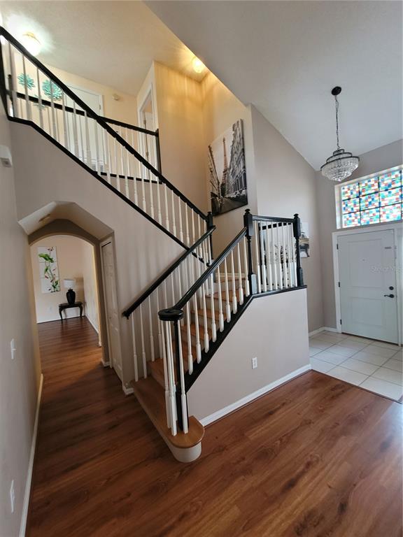 A foyer features a staircase with black railings, wood flooring, and a stained-glass transom window — 27640 BREAKERS DRIVE, WESLEY CHAPEL, FL