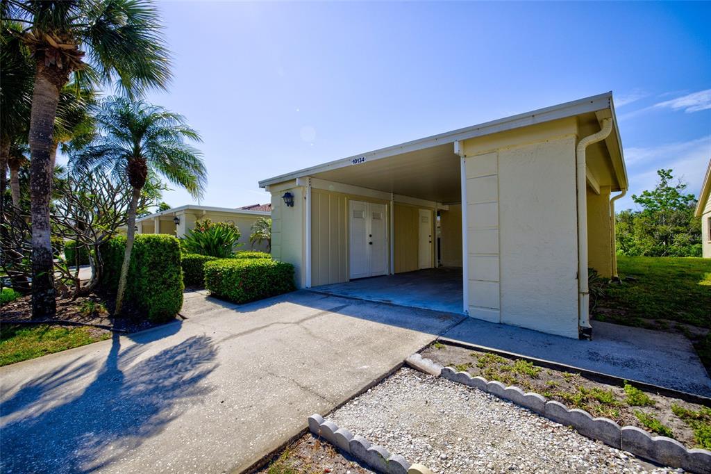 A light-colored house exterior features a covered carport and a concrete driveway — 10134 REGAL DRIVE UNIT 1, LARGO, FL