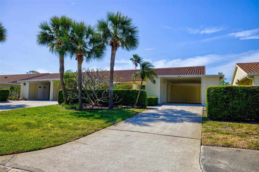 A single-story house with a carport, palm trees, and a manicured hedge in front — 10134 REGAL DRIVE UNIT 1, LARGO, FL