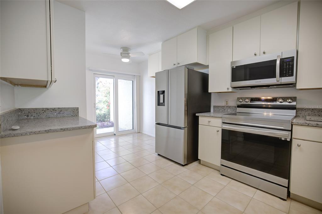 A kitchen with white cabinets, stainless steel appliances, granite countertops, and tile flooring — 10134 REGAL DRIVE UNIT 1, LARGO, FL