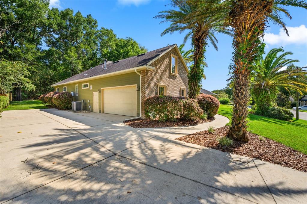 An exterior view of a detached garage with green siding, brick accents, and a concrete driveway — 7560 WHITE OAKS ROAD, ALACHUA, FL