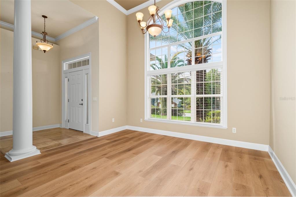 A bright room with light wood flooring, a tall arched window, and a chandelier — 7560 WHITE OAKS ROAD, ALACHUA, FL