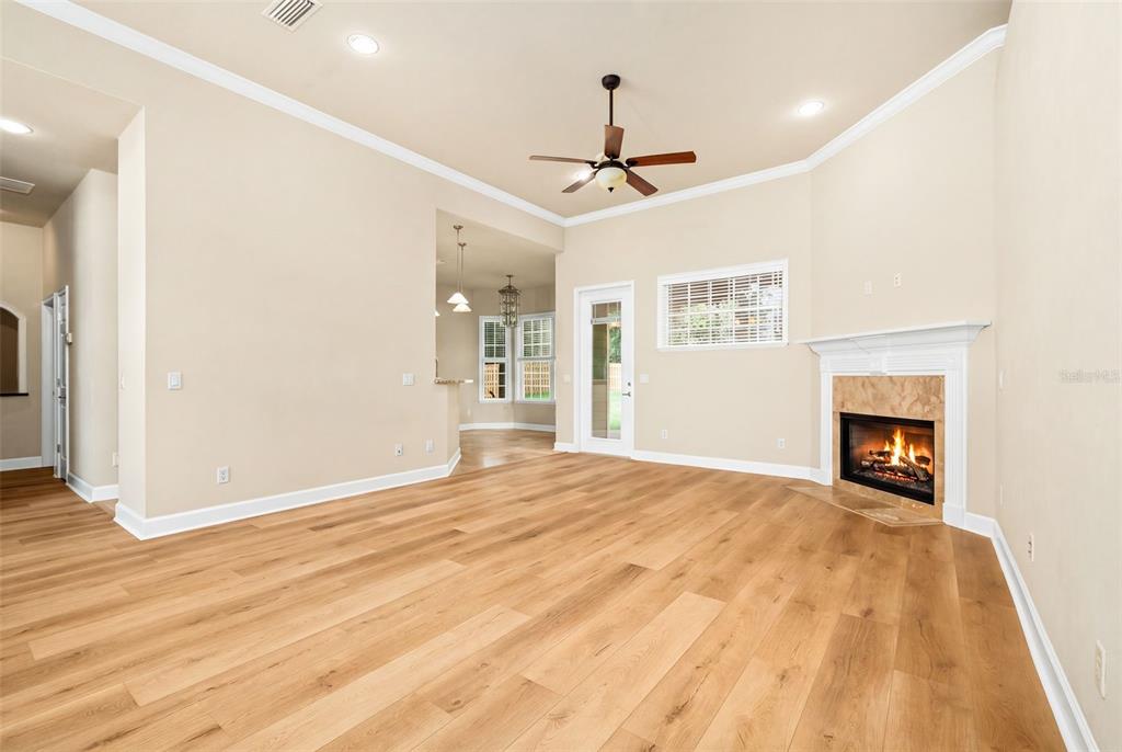 A spacious living room features light wood flooring, a fireplace, and a ceiling fan — 7560 WHITE OAKS ROAD, ALACHUA, FL