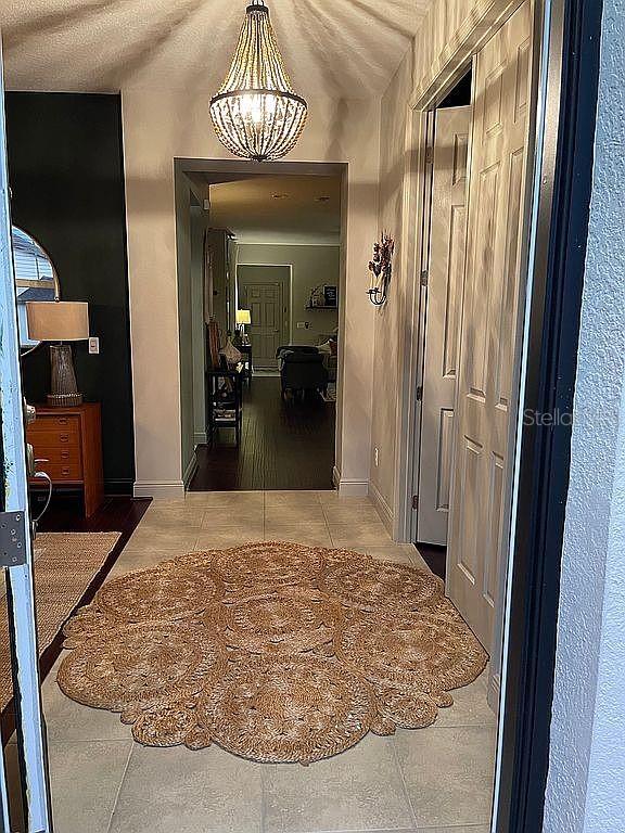 A foyer features a beaded chandelier, a round jute rug, and a view into a hallway — 960 SEBURN ROAD, APOPKA, FL