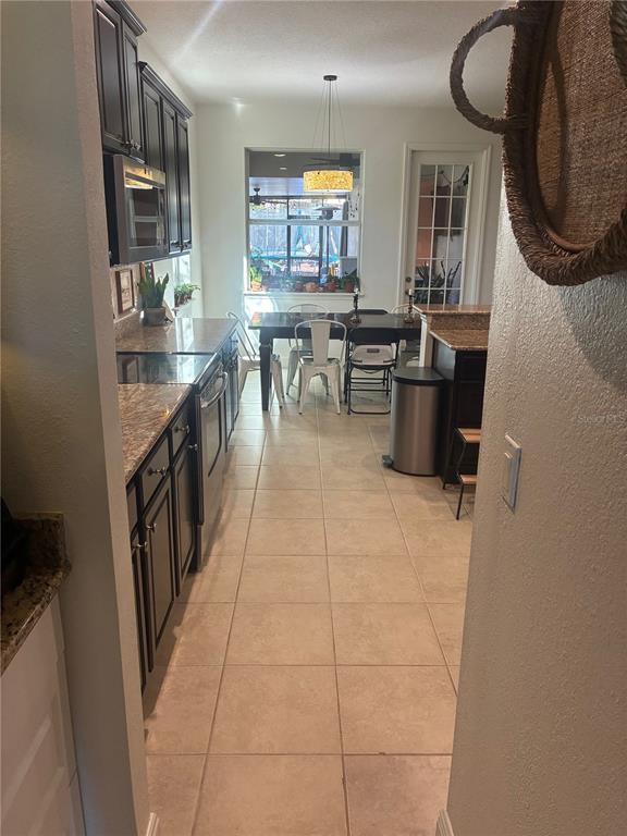 A kitchen with dark cabinets and granite countertops leads to a dining area with tile floors — 960 SEBURN ROAD, APOPKA, FL
