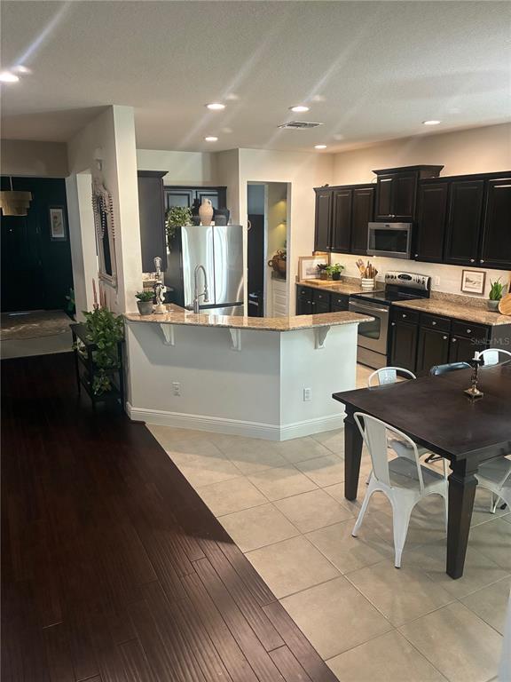 A kitchen features dark wood cabinets, granite countertops, a breakfast bar, and tile flooring — 960 SEBURN ROAD, APOPKA, FL