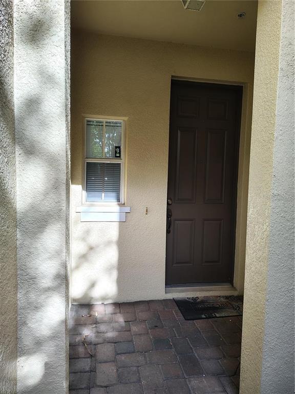 A brown front door and a small window are set within a recessed entryway — 6043 STRADA ISLE WAY, ORLANDO, FL
