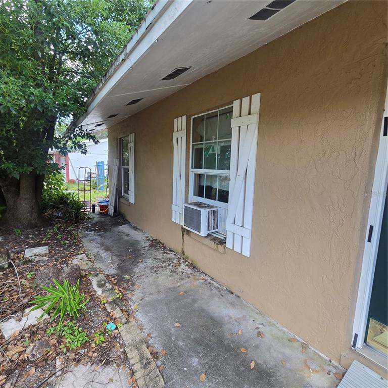 An exterior view of a tan stucco house wall with two windows and white shutters — 5127 BLACK BIRCH TRAIL, MULBERRY, FL