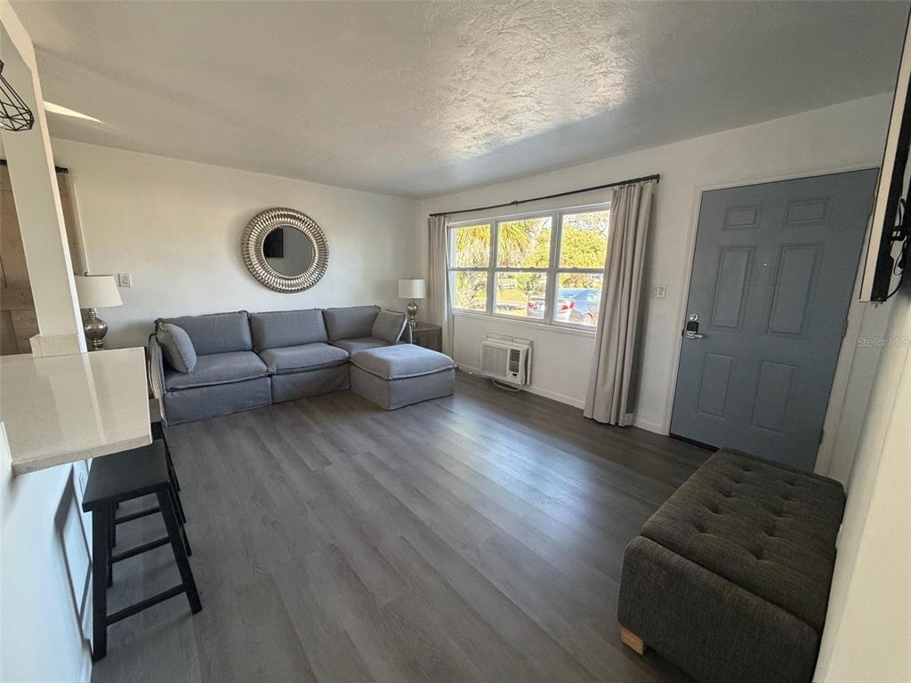 A living room features gray wood-look flooring, a sectional sofa, a blue door, and windows — 9372 88TH WAY, SEMINOLE, FL