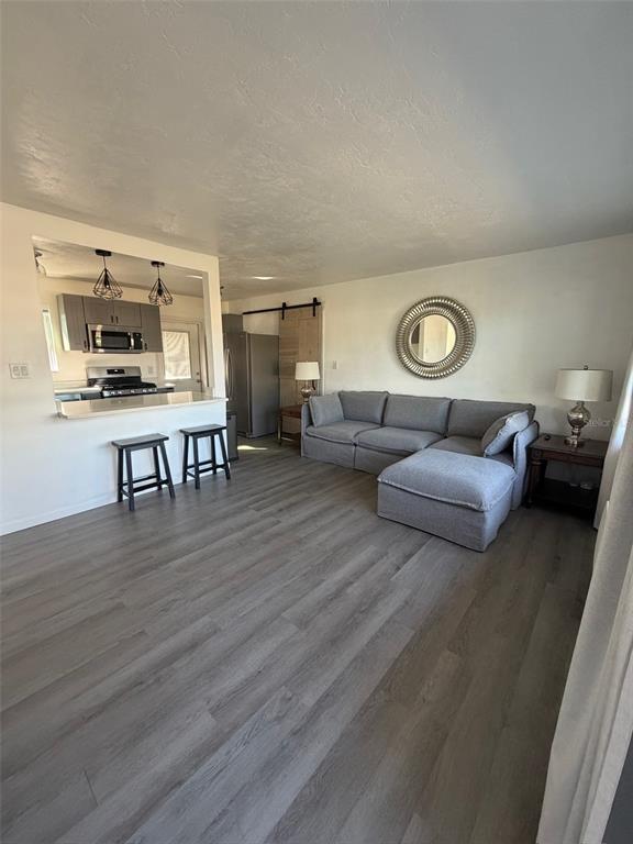 A living room with gray flooring, a sectional sofa, and an open kitchen with bar seating — 9372 88TH WAY, SEMINOLE, FL