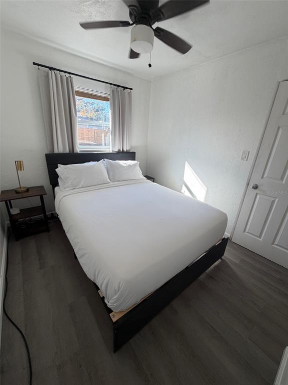 A bedroom features a bed with white linens, a dark frame, and light wood flooring — 9372 88TH WAY, SEMINOLE, FL