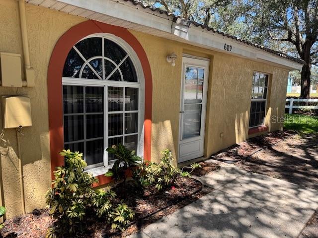 The exterior of a yellow stucco house features an arched window and a white door — 689 LAKE MARION GOLF RESORT, KISSIMMEE, FL