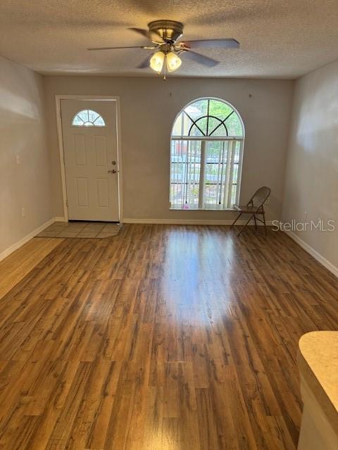 An empty living room features wood-look flooring, a ceiling fan, an arched window, and a door — 689 LAKE MARION GOLF RESORT, KISSIMMEE, FL