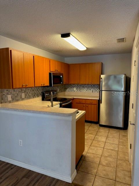 A kitchen features wood cabinets, stainless steel appliances, a tiled backsplash, and a breakfast bar — 689 LAKE MARION GOLF RESORT, KISSIMMEE, FL
