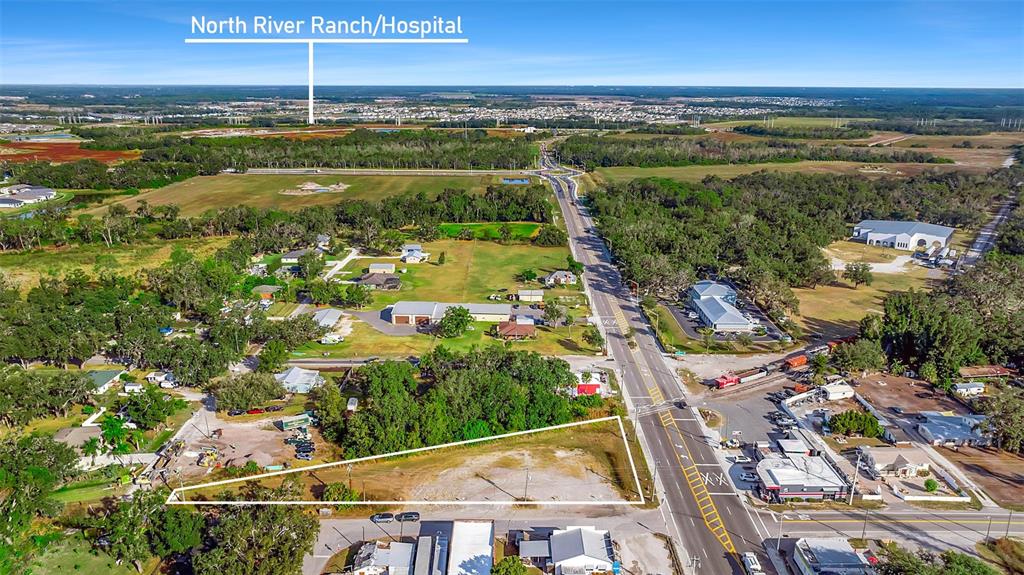 An aerial view shows a vacant, triangular-shaped lot adjacent to a road and nearby buildings — 12346 US-301, PARRISH, FL