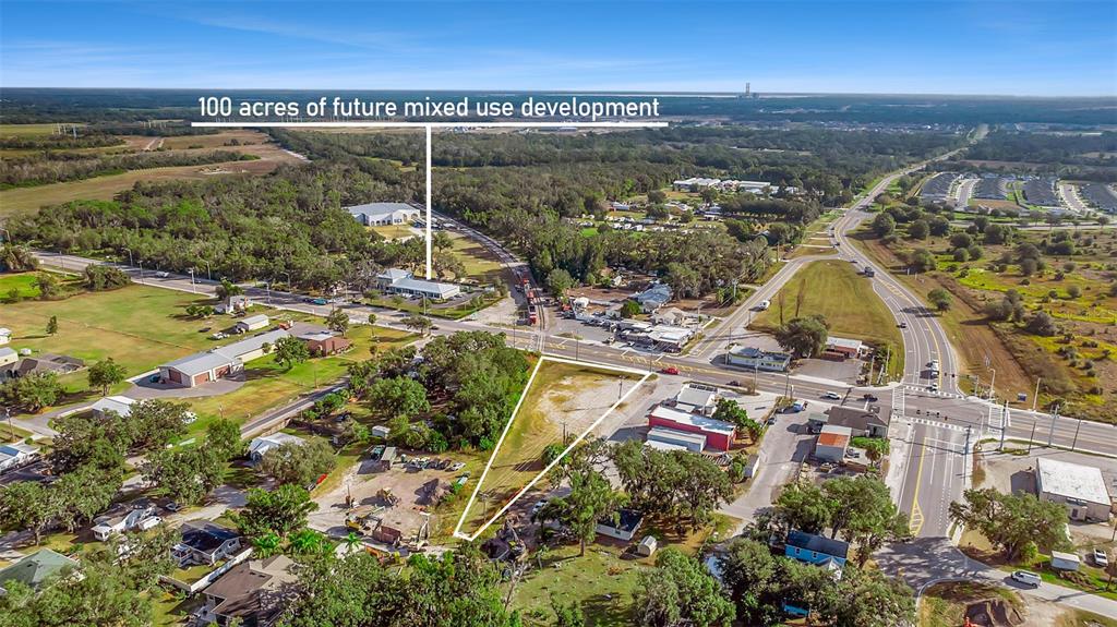 An aerial view shows a triangular vacant lot near a road intersection and forested land — 12346 US-301, PARRISH, FL