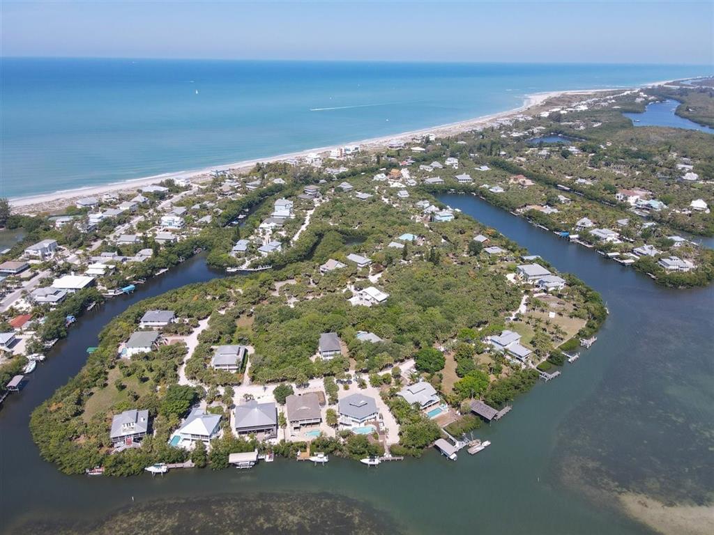 An aerial view shows waterfront houses nestled among trees along a canal and the coast — 14 BAYSHORE CIRCLE, PLACIDA, FL