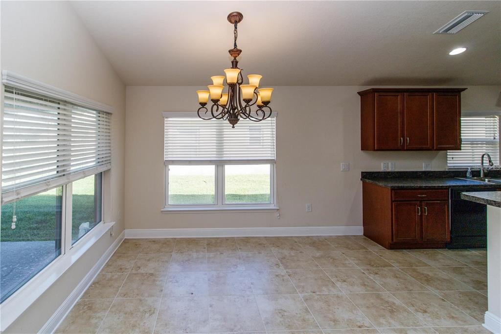 A dining area features tile flooring, a chandelier, and an adjacent kitchen with dark cabinets — 13541 NITI DRIVE, HUDSON, FL
