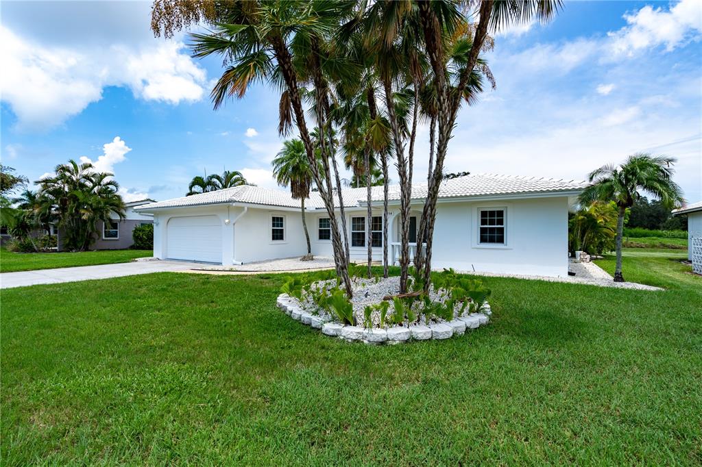 A white single-story house with a two-car garage and a palm tree garden in front — 7354 BILTMORE DRIVE, SARASOTA, FL