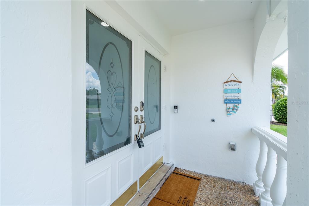 A white double front door with glass inserts opens onto a covered porch area — 7354 BILTMORE DRIVE, SARASOTA, FL
