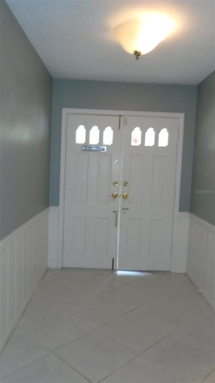An entryway features white double doors, light-colored tile flooring, and gray walls with white wainscoting — 2330 MOHAWK TRAIL, MAITLAND, FL