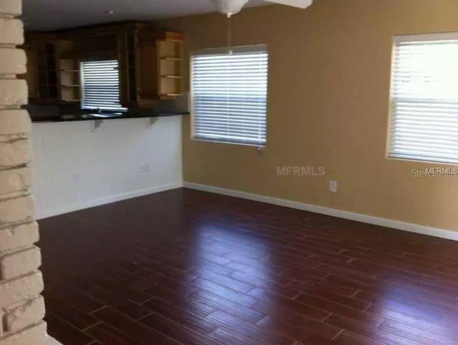 A room with dark wood-look flooring, tan walls, and a kitchen counter in the background — 2330 MOHAWK TRAIL, MAITLAND, FL