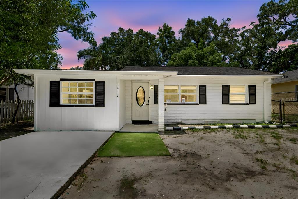 A single-story white house with black shutters and a small patch of artificial turf — 1614 E MAPLE AVENUE, TAMPA, FL