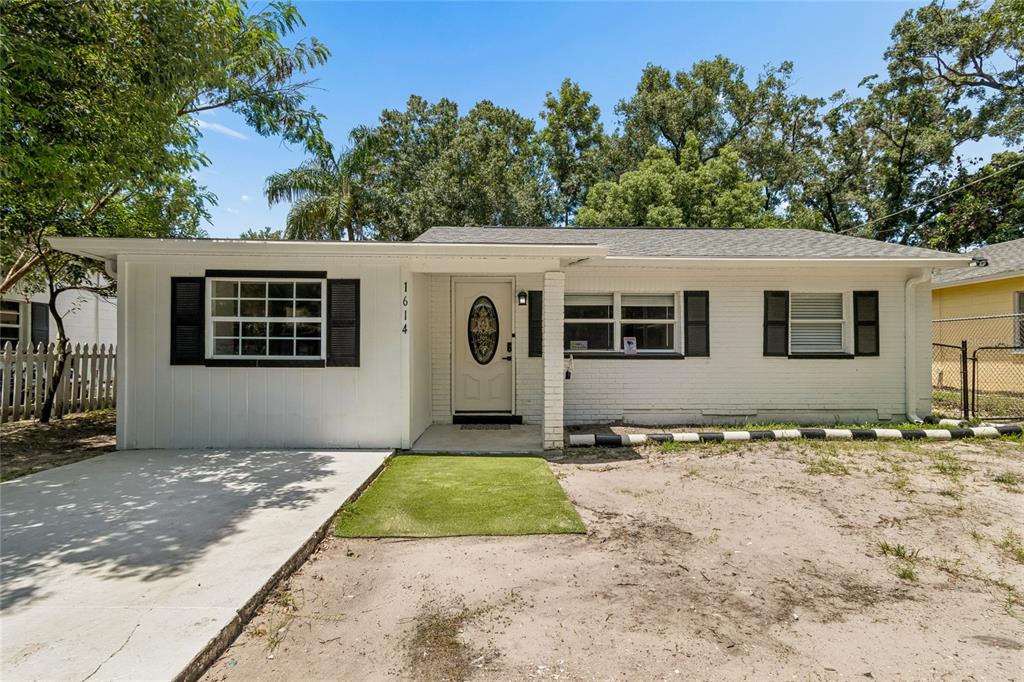 A white, single-story house with black shutters and a small patch of artificial turf — 1614 E MAPLE AVENUE, TAMPA, FL