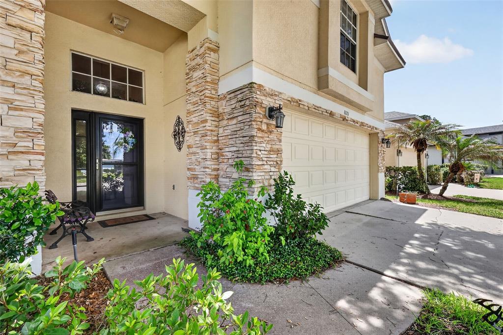 The exterior of a two-story home features a stone-accented facade, a garage, and an entryway — 8051 SAINT JAMES WAY, MOUNT DORA, FL