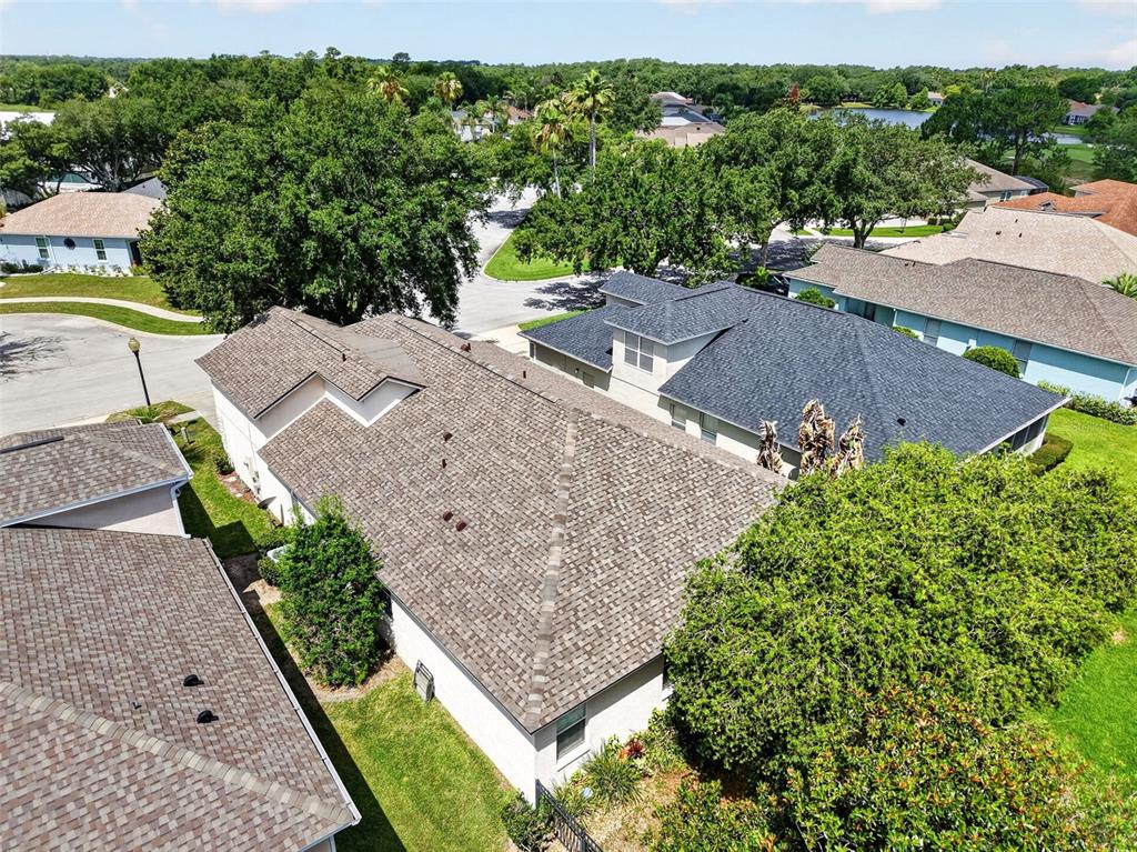 An aerial view shows the shingled roofs of several suburban houses surrounded by green trees — 8051 SAINT JAMES WAY, MOUNT DORA, FL