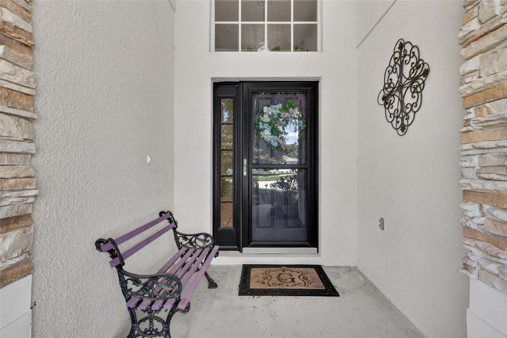 A front entryway features a black storm door, a purple bench, and stone-accented walls — 8051 SAINT JAMES WAY, MOUNT DORA, FL