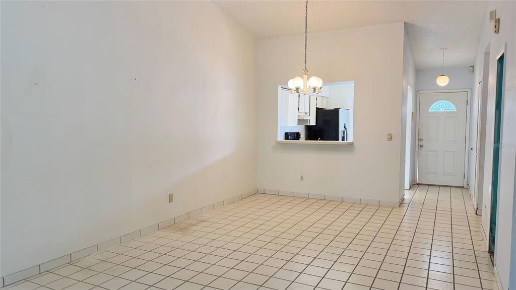 A dining area with white tile floors, a pass-through window to the kitchen, and a chandelier — 762 KINGS COVE COURT, ORLANDO, FL