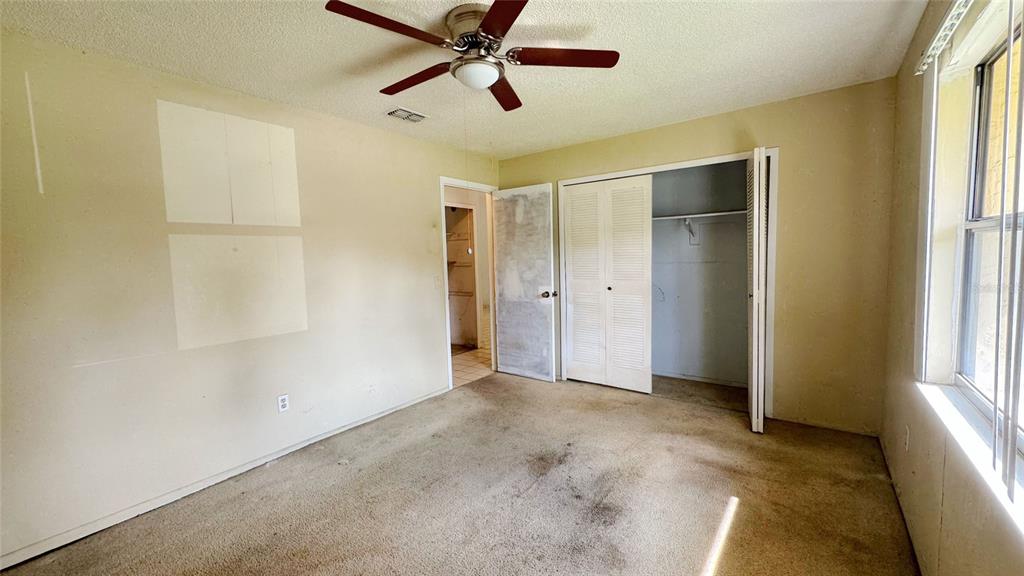 A bedroom with beige walls, a ceiling fan, a closet, and stained wall-to-wall carpeting — 762 KINGS COVE COURT, ORLANDO, FL