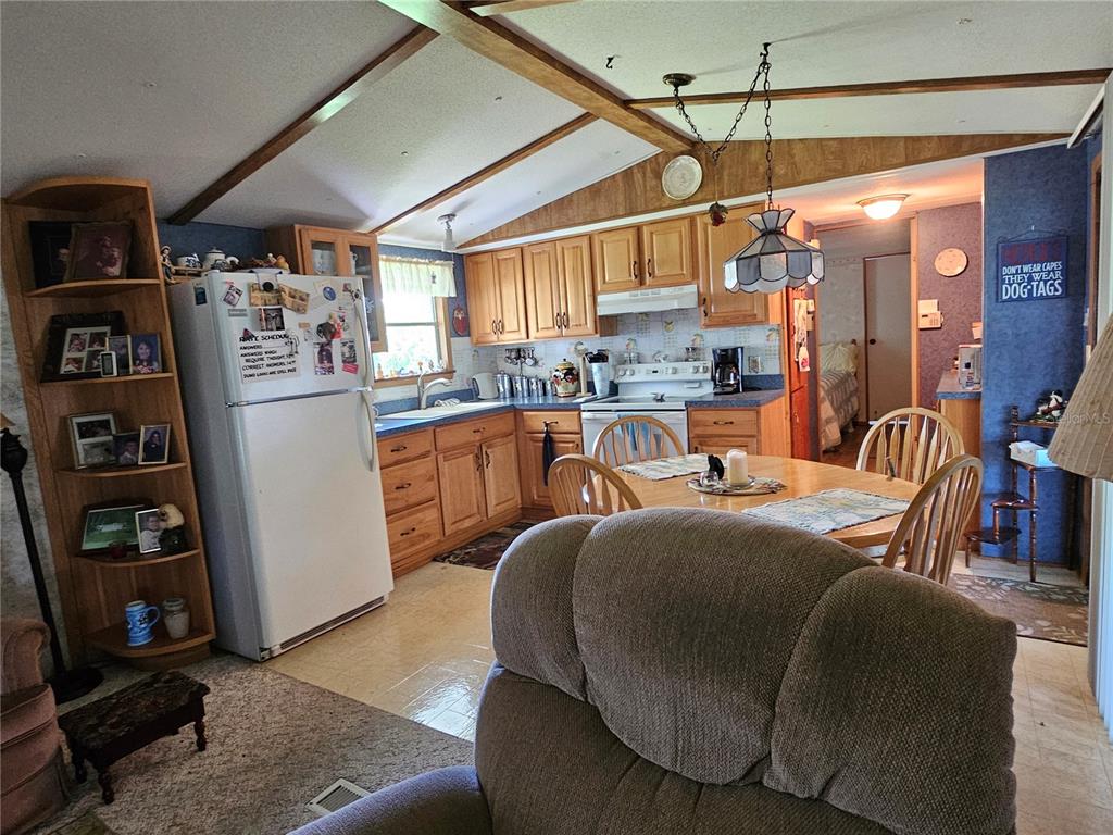 A kitchen with wood cabinets and a dining area is visible from a living room — 2144 LOIS BOULEVARD, LAKE ALFRED, FL