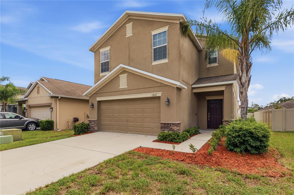 A two-story tan stucco house with a two-car garage and a front walkway — 13822 REINDEER CIRCLE, HUDSON, FL