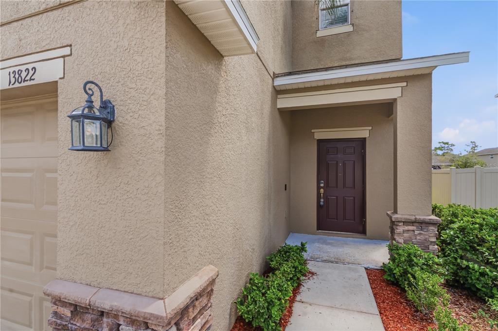 The exterior of a house features a brown front door, stucco walls, and stone accents — 13822 REINDEER CIRCLE, HUDSON, FL