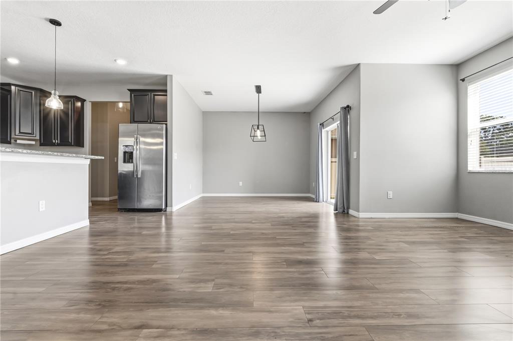 An open-concept dining area features wood-look flooring, gray walls, and a modern pendant light — 13822 REINDEER CIRCLE, HUDSON, FL