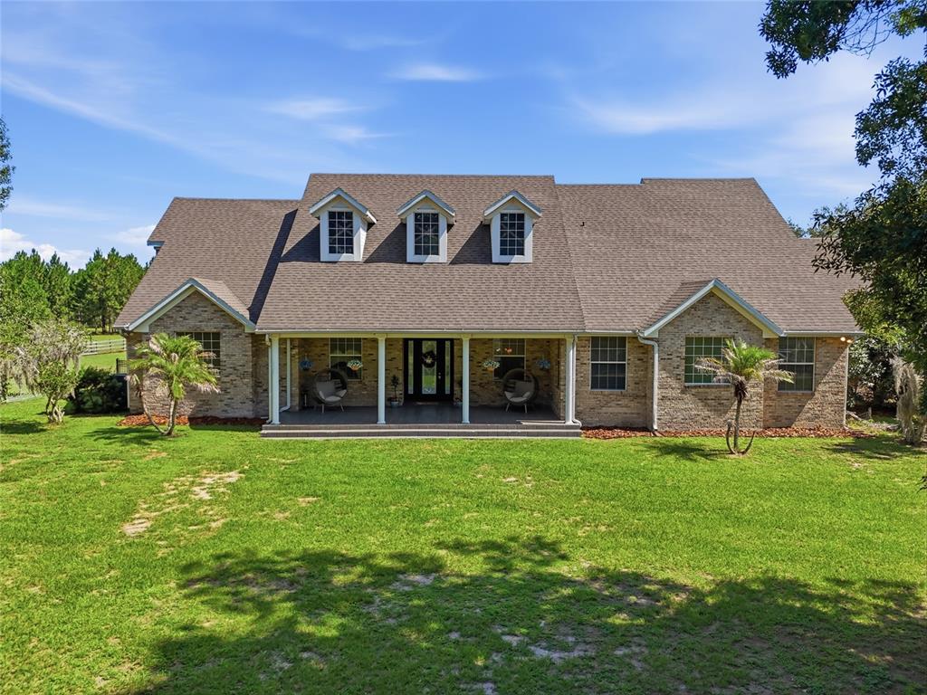 A two-story brick house with a covered front porch and three dormer windows — 13525 PALM DRIVE, ASTATULA, FL
