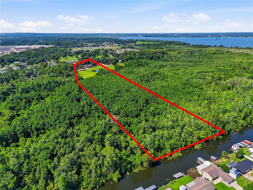 An aerial view shows a house, a red barn, and a pond on a grassy lot — 13525 PALM DRIVE, ASTATULA, FL