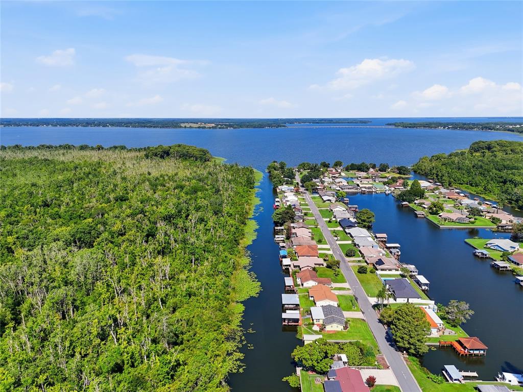 An aerial view shows a residential street alongside a canal leading to a large lake — 13525 PALM DRIVE, ASTATULA, FL