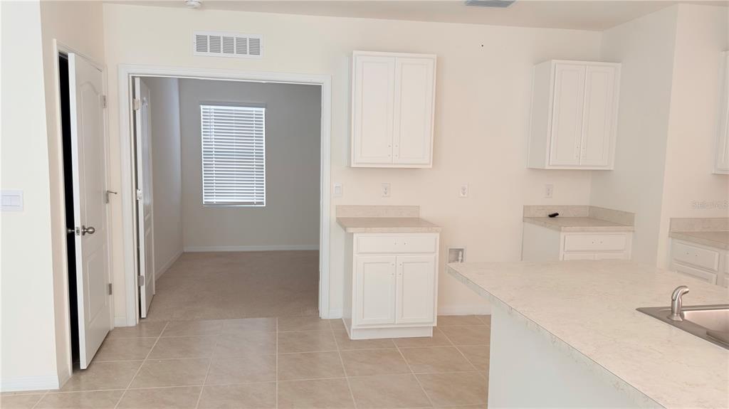A kitchen with white cabinets, light countertops, and a doorway leading to a carpeted room — 2816 SWOOPING SPARROW DRIVE, ST CLOUD, FL