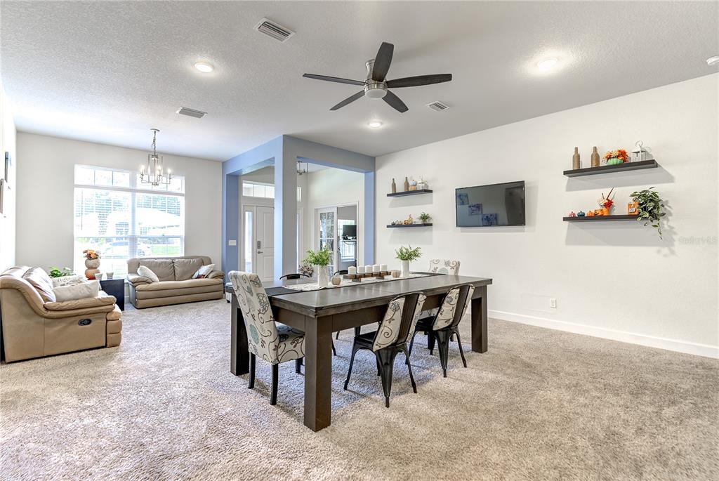 A dining area with a wooden table and chairs sits in an open-concept living space — 71 BELLS OF IRELAND COURT, HOMOSASSA, FL