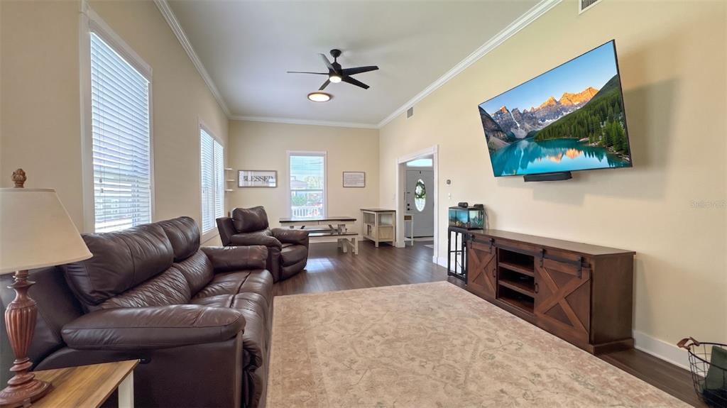 A living room features a leather sofa, a television mounted on the wall, and wood flooring — 520 S JACKSON AVENUE, BARTOW, FL