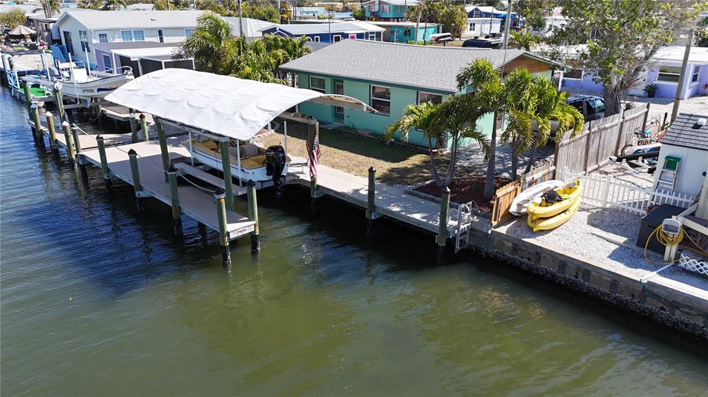 An aerial view shows a waterfront house with a boat lift and two yellow kayaks — 2650 COCO PLUM DRIVE, MATLACHA, FL