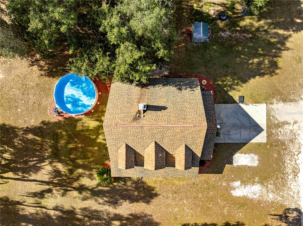 An aerial view shows a house with a shingled roof, a pool, and a shed — 13850 NE 47TH AVENUE, ANTHONY, FL