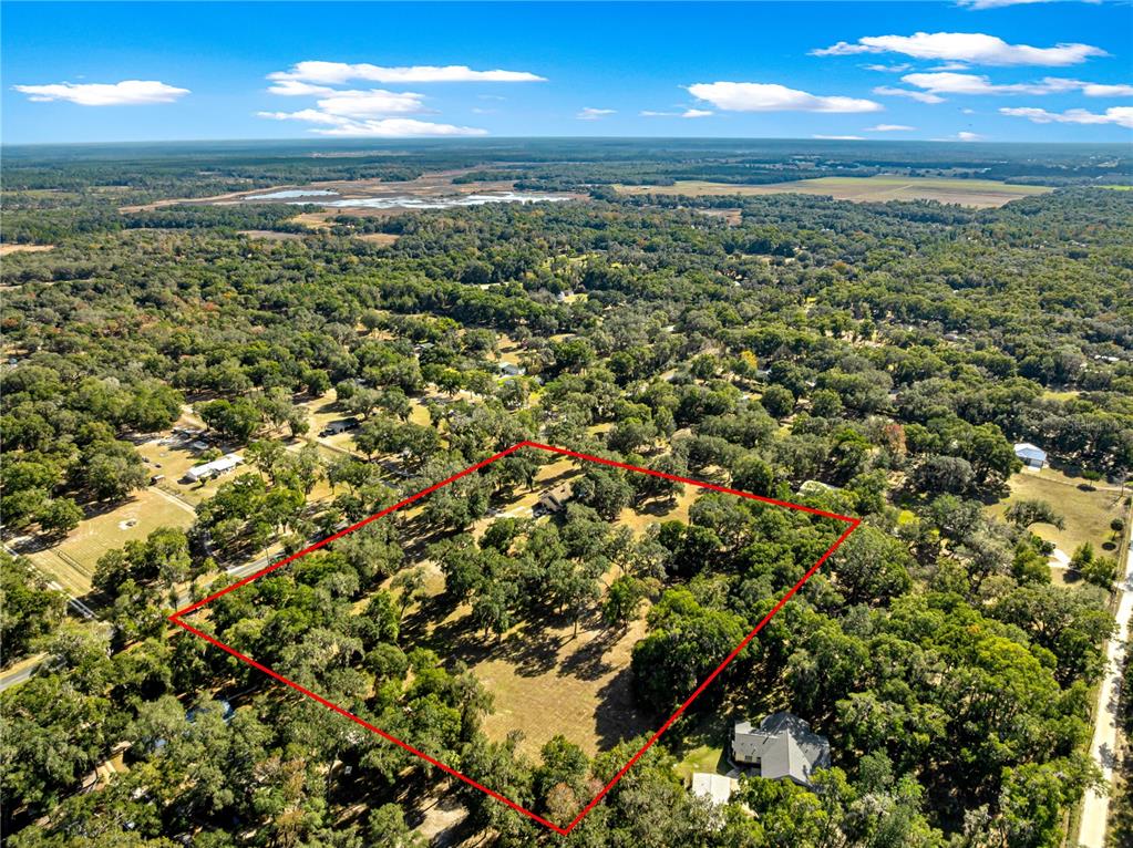 An aerial view shows a wooded residential lot outlined in red with a house — 13850 NE 47TH AVENUE, ANTHONY, FL