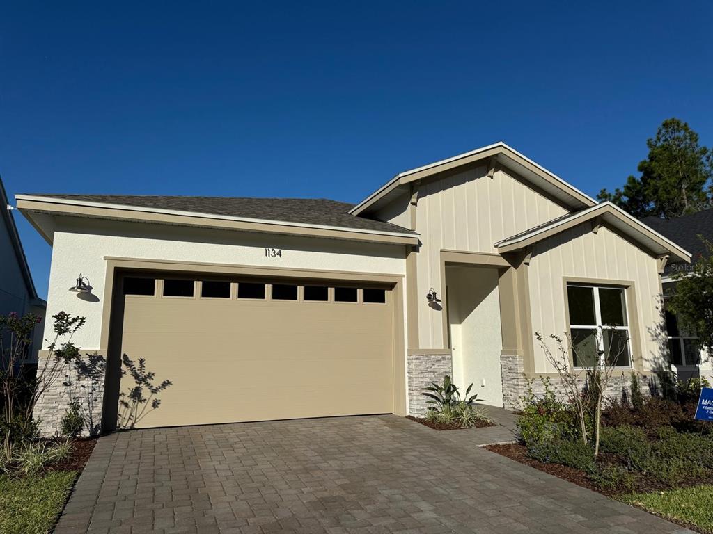 A single-story house with a beige garage, white vertical siding, and stone accents on the exterior — 1134 CLIFFHAVEN COURT, ORMOND BEACH, FL