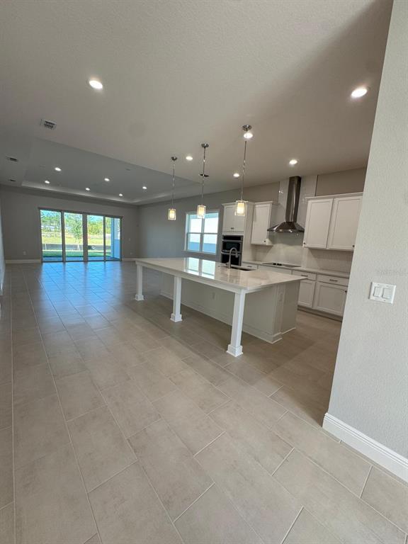 A modern kitchen with a large island and white cabinetry opens into a spacious living area — 1134 CLIFFHAVEN COURT, ORMOND BEACH, FL